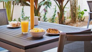 An outdoor dining area with a table, chairs, a bowl of fruit, a glass of orange juice, and a coffee cup. - Residence Inn by Marriott West Palm Beach Downtown (West Palm Beach)