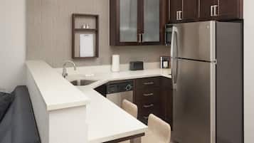 A modern kitchen with a built-in dishwasher, a stainless steel refrigerator, and dark wooden cabinets.