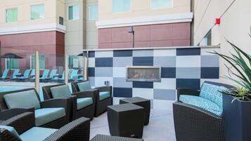 A hotel patio with wicker furniture, a checkered wall, and a fire feature.