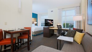 Ein Hotelzimmer mit Bett, Schreibtisch, Fernseher, Sofa und einem Fenster mit Blick.