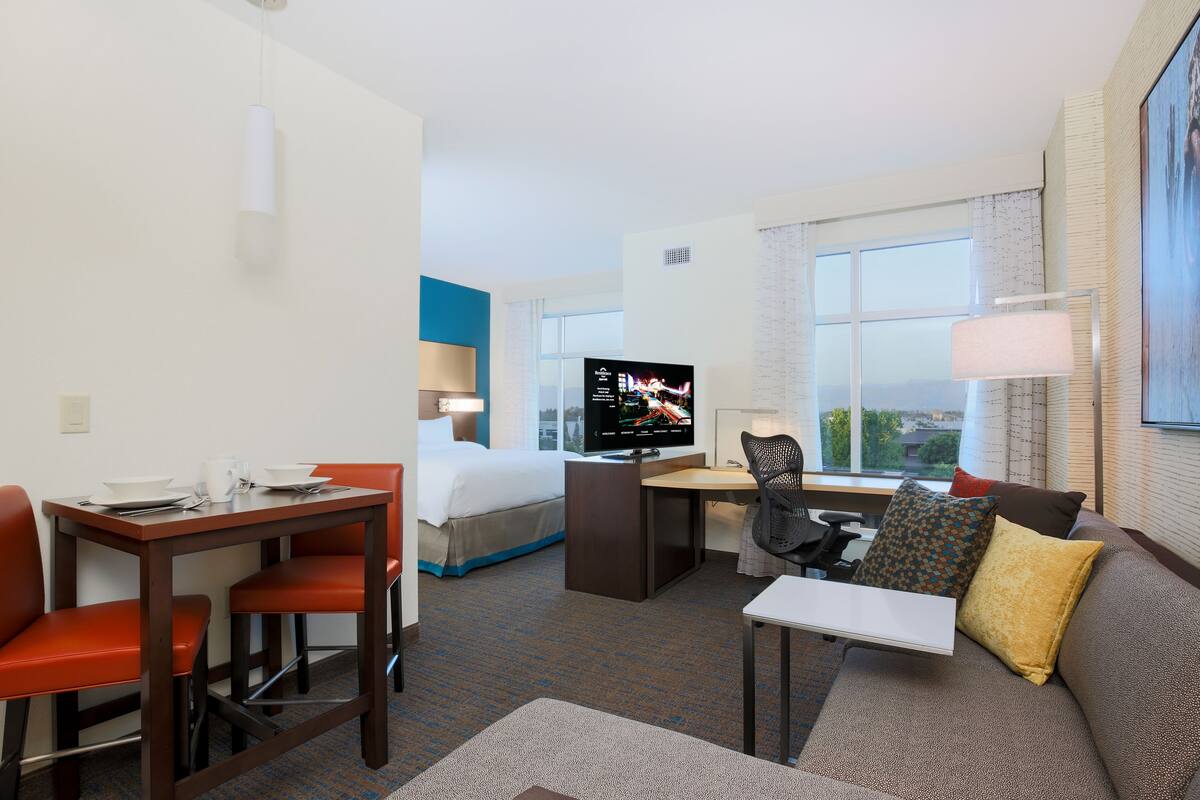 Une chambre d’hôtel équipée d’un lit, d’un bureau, d’une télévision, d’un canapé et d’une fenêtre donnant sur un paysage agréable.