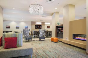 Een moderne lobby met een zithoek, een bar en een open haard.