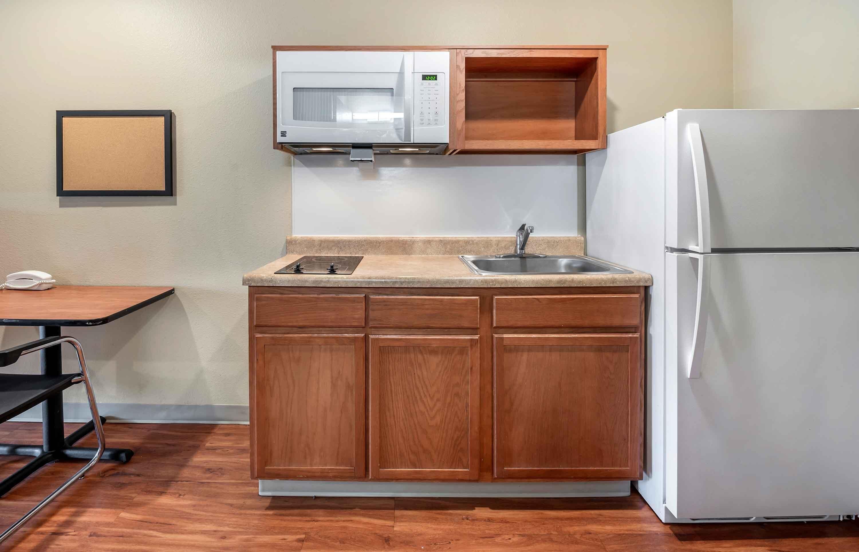 Una cocina compacta equipada con microondas, lavamanos y refrigerador.