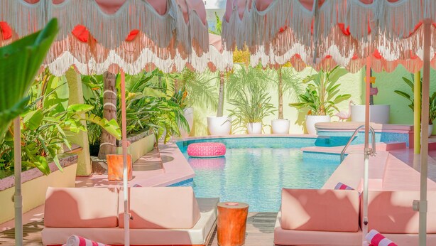 A poolside area with lounge chairs, umbrellas, and potted plants. - Tropicana Ibiza Suites - Adults Only (Sant Josep de sa Talaia)