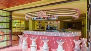 A bar area with a neon sign, multiple stools, and a counter with bottles. - Tropicana Ibiza Suites - Adults Only (Sant Josep de sa Talaia)