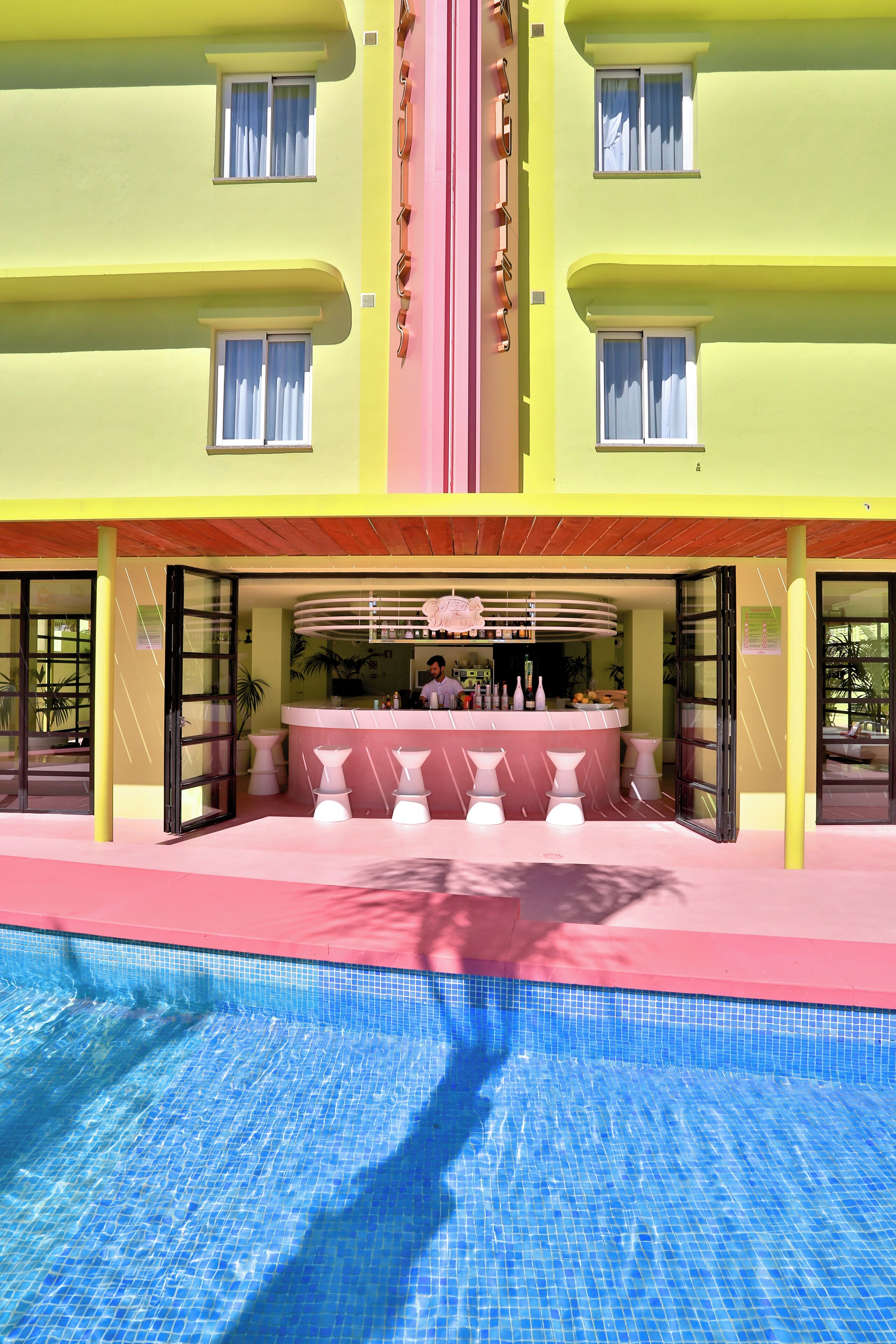 Un hotel con piscina, bar y zona de recepción.