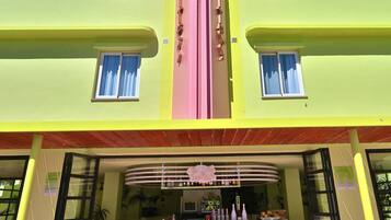 A multi-story building with a central pink and yellow facade, featuring a bar area with white stools and a counter.