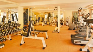 Un gimnasio con diverso equipamiento de ejercicios, incluyendo cintas de correr, máquinas de pesas y mancuernas.