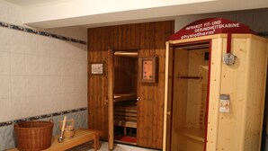Un cuarto de sauna con un banco de madera, una cesta y un armario de madera.