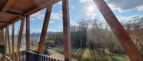 Un balcón de madera con vistas a un bosque y montañas.