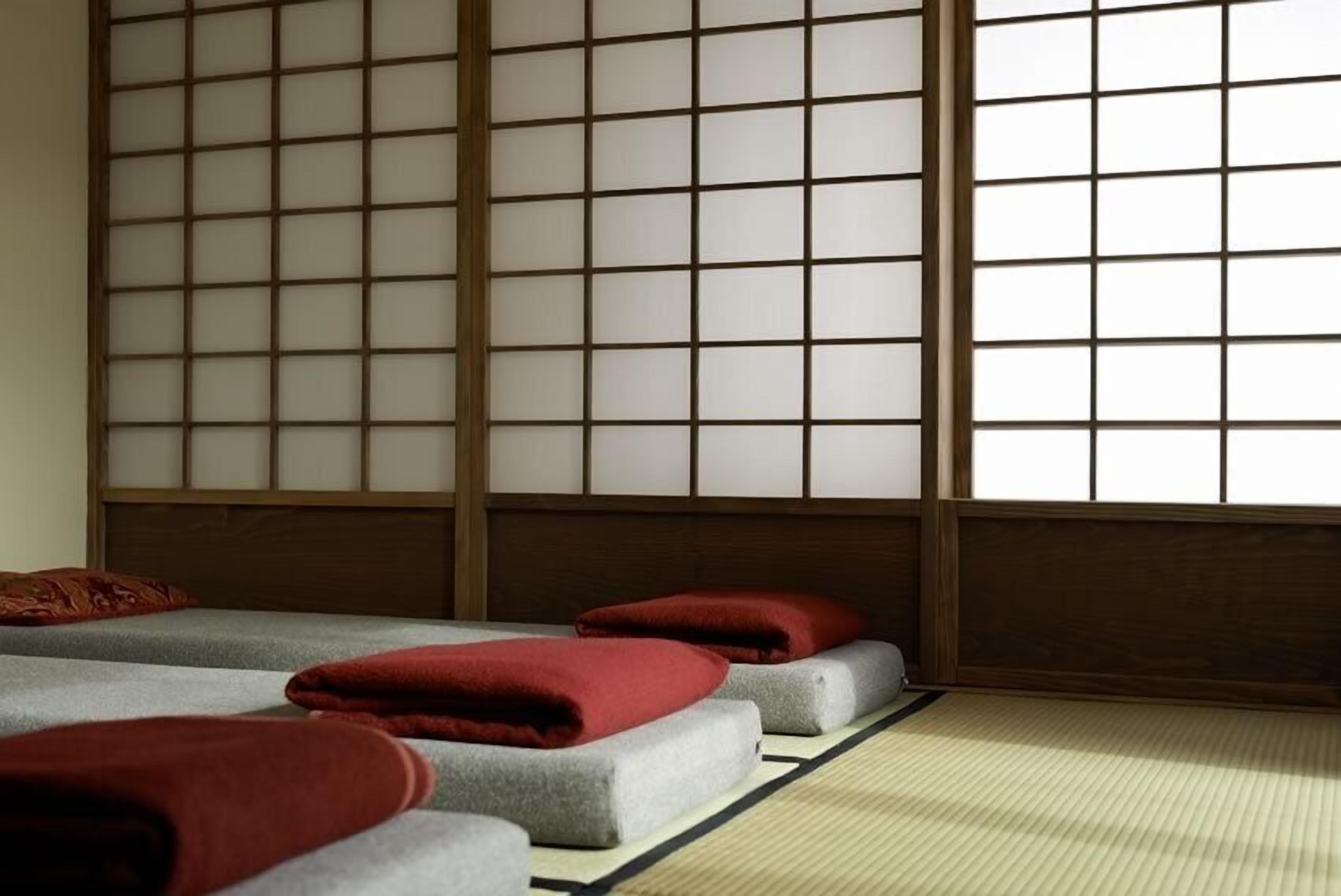 Ein traditioneller japanischer Raum mit Tatami-Böden, einem niedrigen Holzbettgestell und einem verschiebbaren Shoji-Bildschirm.