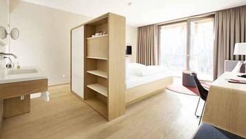 A hotel room with a bed, a desk, a chair, a wardrobe, a mirror, and a window.