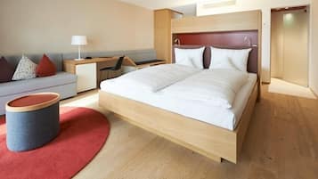Ein modernes Hotelzimmer mit einem großen Bett, einem Schreibtisch, einer Couch und einem kleinen Tisch.