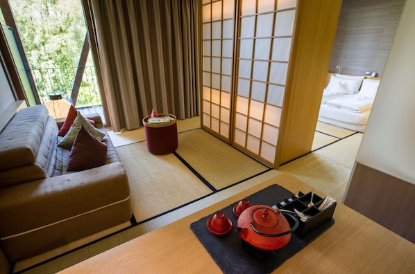 A traditional Japanese room with tatami flooring, a low table with a red tea set, and a sliding shoji screen door. - Hotel Bora HotSpaResort (Radolfzell am Bodensee)
