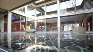 A modern building with large glass windows and a reflective stone floor. - Hotel Bora HotSpaResort (Radolfzell am Bodensee)