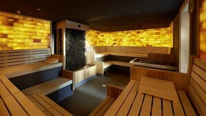 A sauna with wooden benches and a wall with a textured pattern. - Hotel Bora HotSpaResort (Radolfzell am Bodensee)