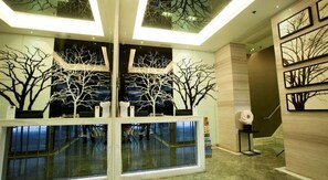 A lobby with a glass partition, a reception desk, and wall-mounted artwork. - M1 Hotel (Kowloon)