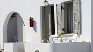 Área da piscina com um prédio branco, um extintor de incêndio e uma porta com portões.