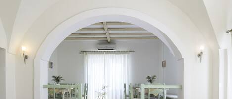 Un comedor amplio con mobiliario blanco y una lámpara central.