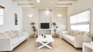 Uma sala de estar moderna com dois sofás, uma mesa de centro e uma TV em uma parede de pedra.