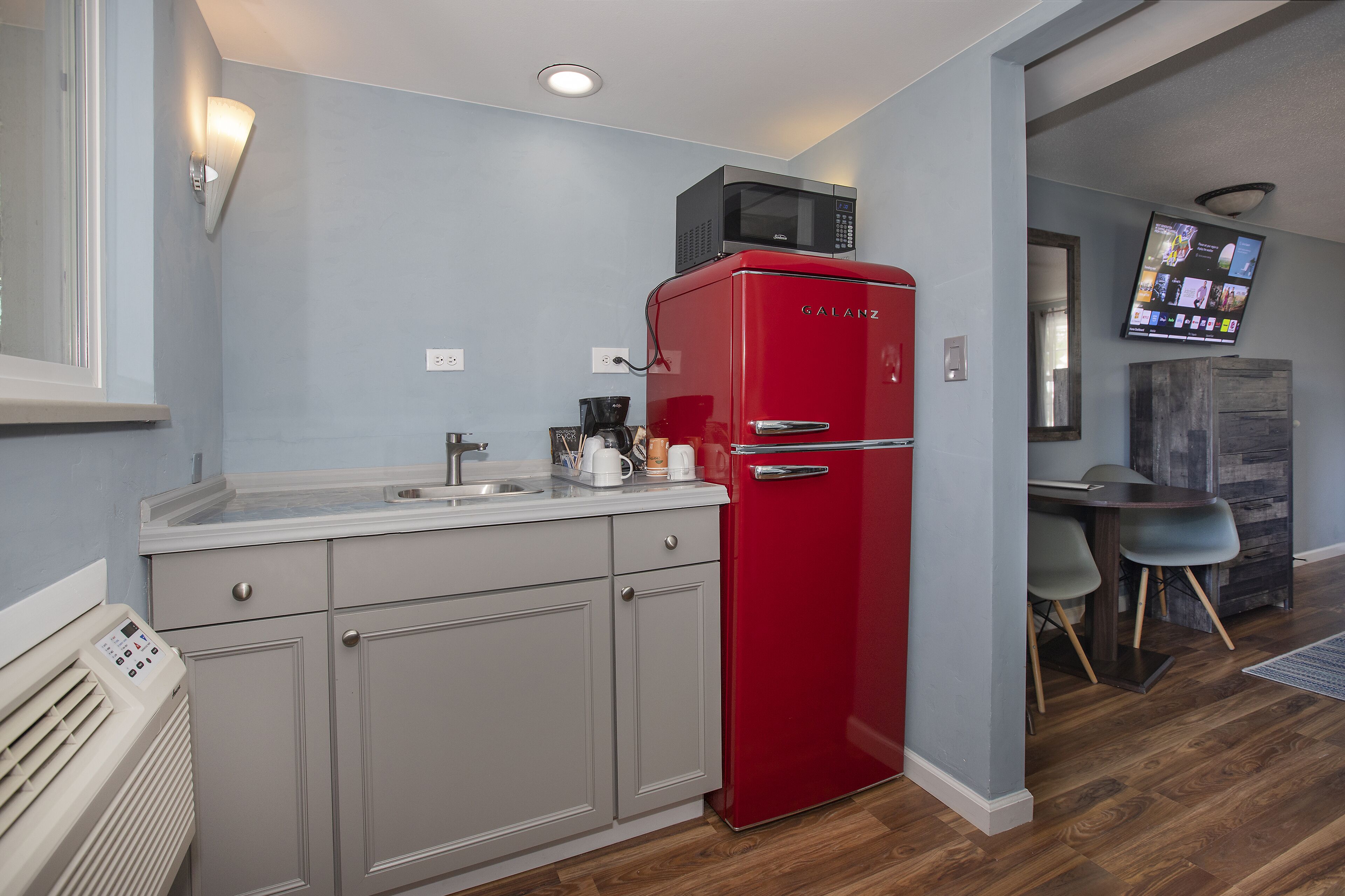 A compact kitchen with a red refrigerator, a microwave, and a coffee maker on the counter.