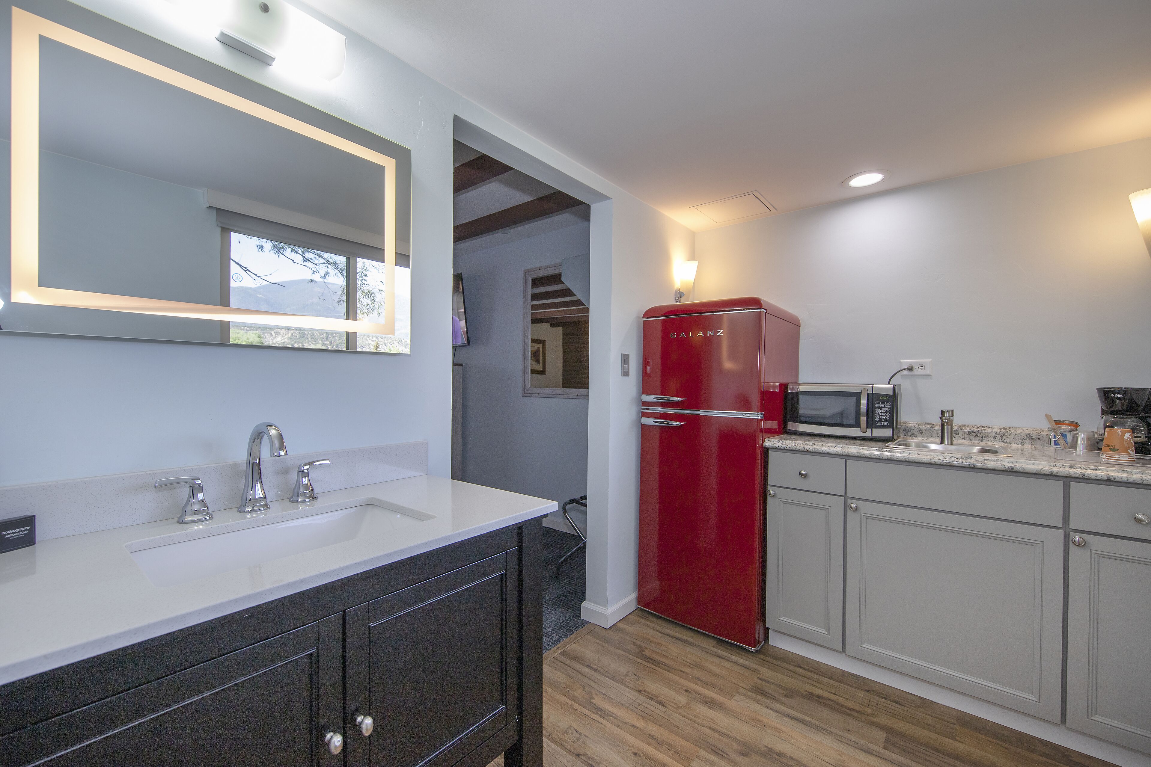 A modern kitchen with a white countertop, a red refrigerator, and a built-in microwave.