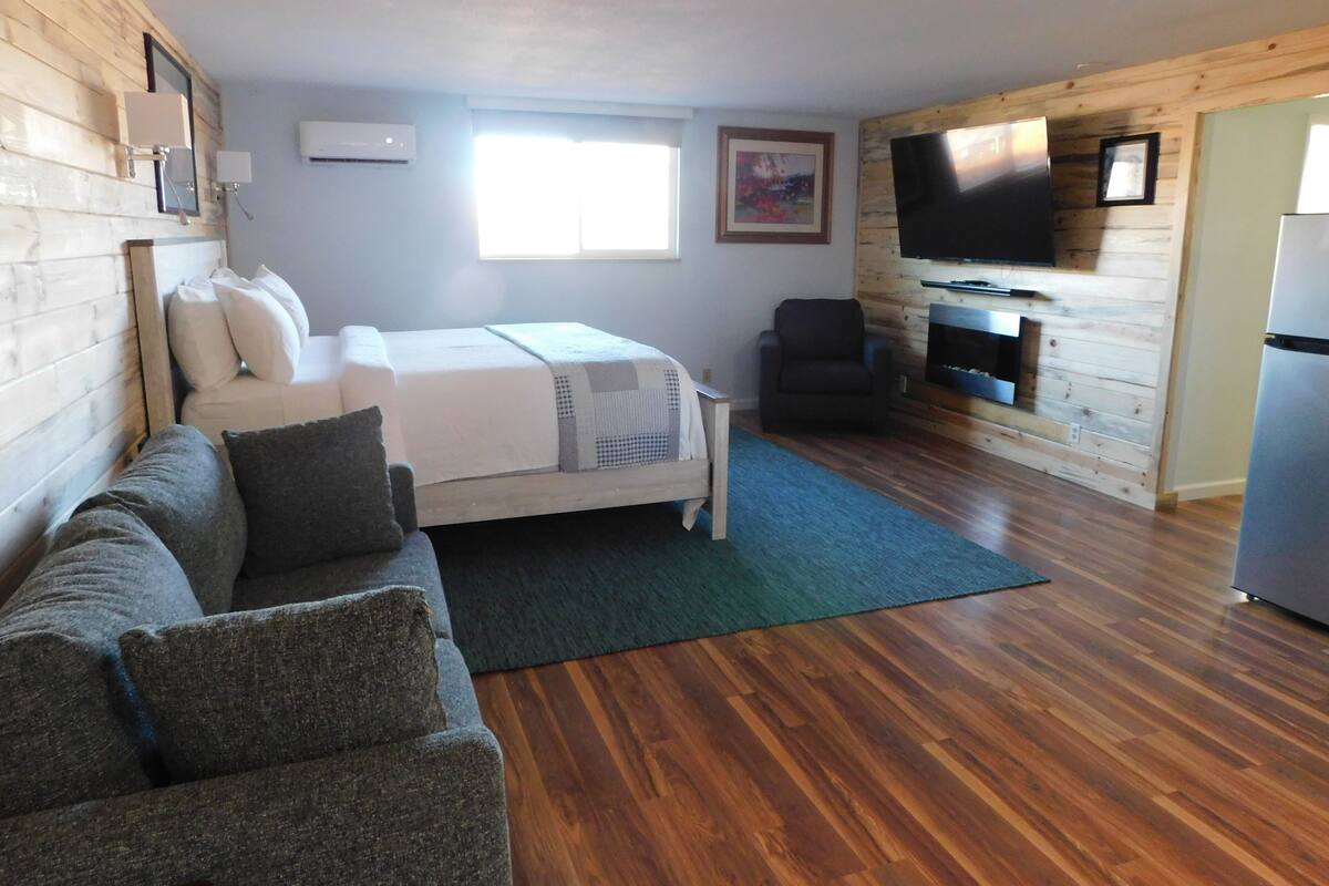Ein gemütliches Zimmer mit Bett, einer Couch, einem Fernseher und einem Kamin.