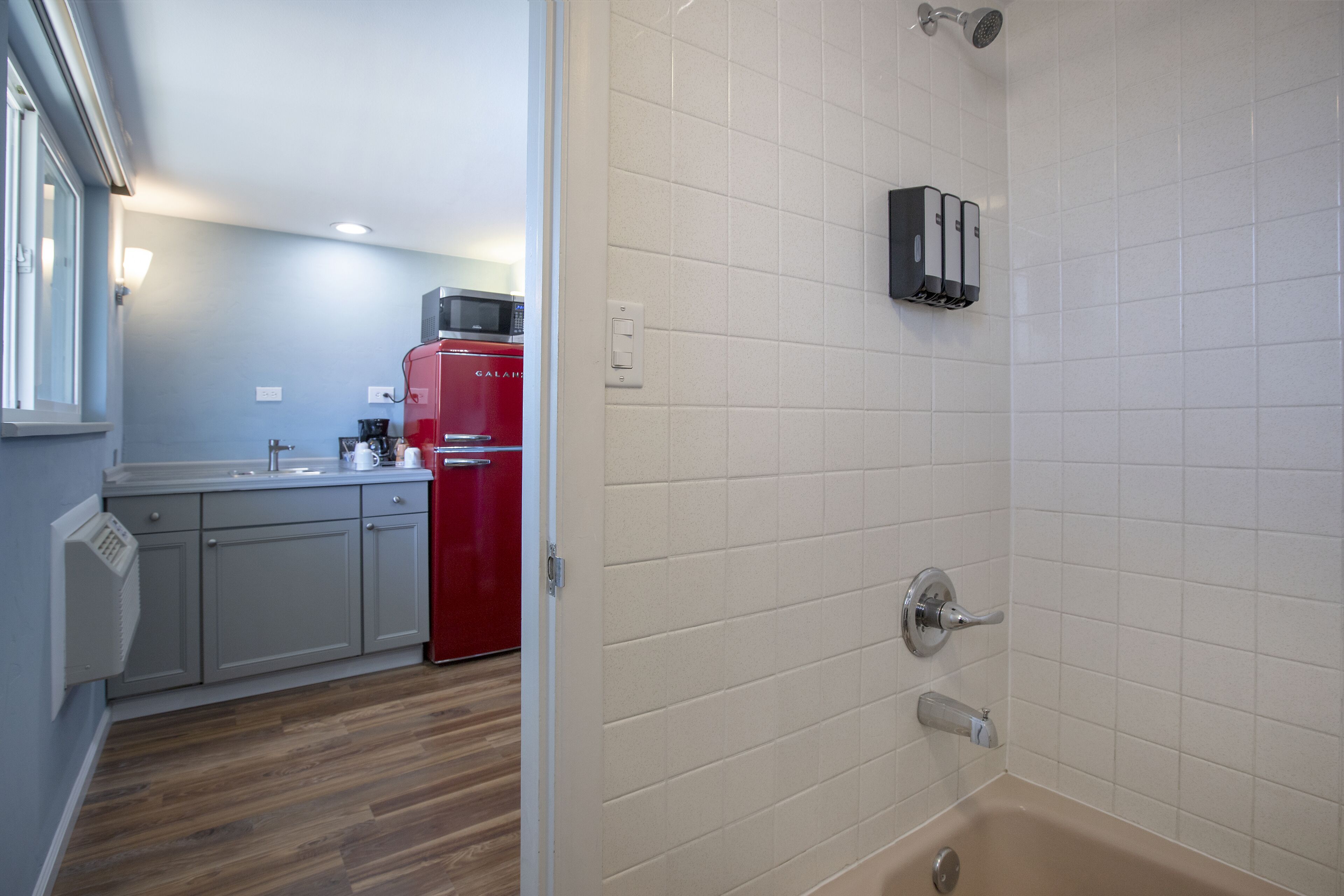 A modern bathroom with white tiles, a bathtub, and a showerhead.