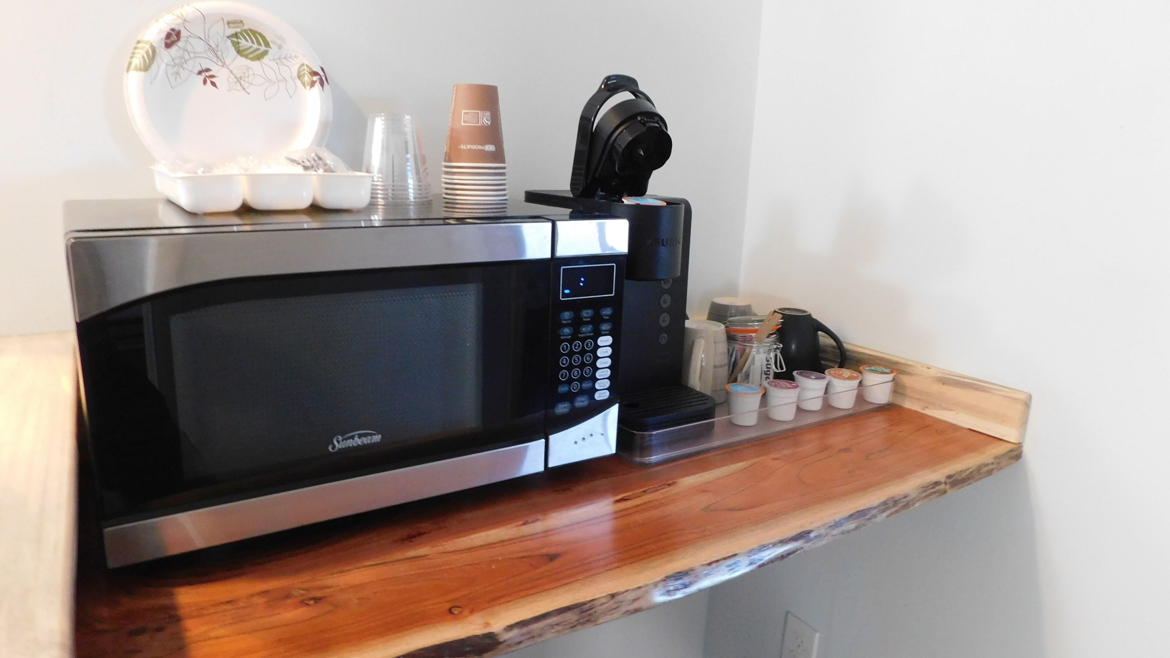 Une cuisine moderne équipée d’un four à micro-ondes encastré, d’une machine à café et d’un ensemble de récipients pour les condiments.