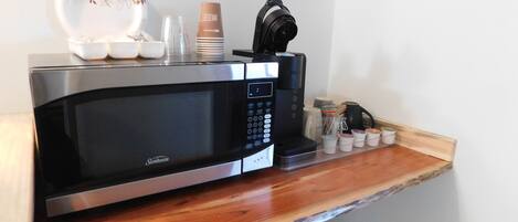 Une cuisine moderne équipée d’un four à micro-ondes encastré, d’une machine à café et d’un ensemble de récipients pour les condiments.