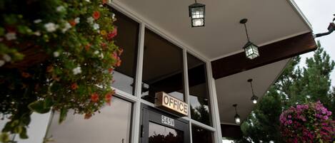 A building with a sign labeled "OFFICE" above the entrance, a number "545W" on the door, and hanging flower baskets.