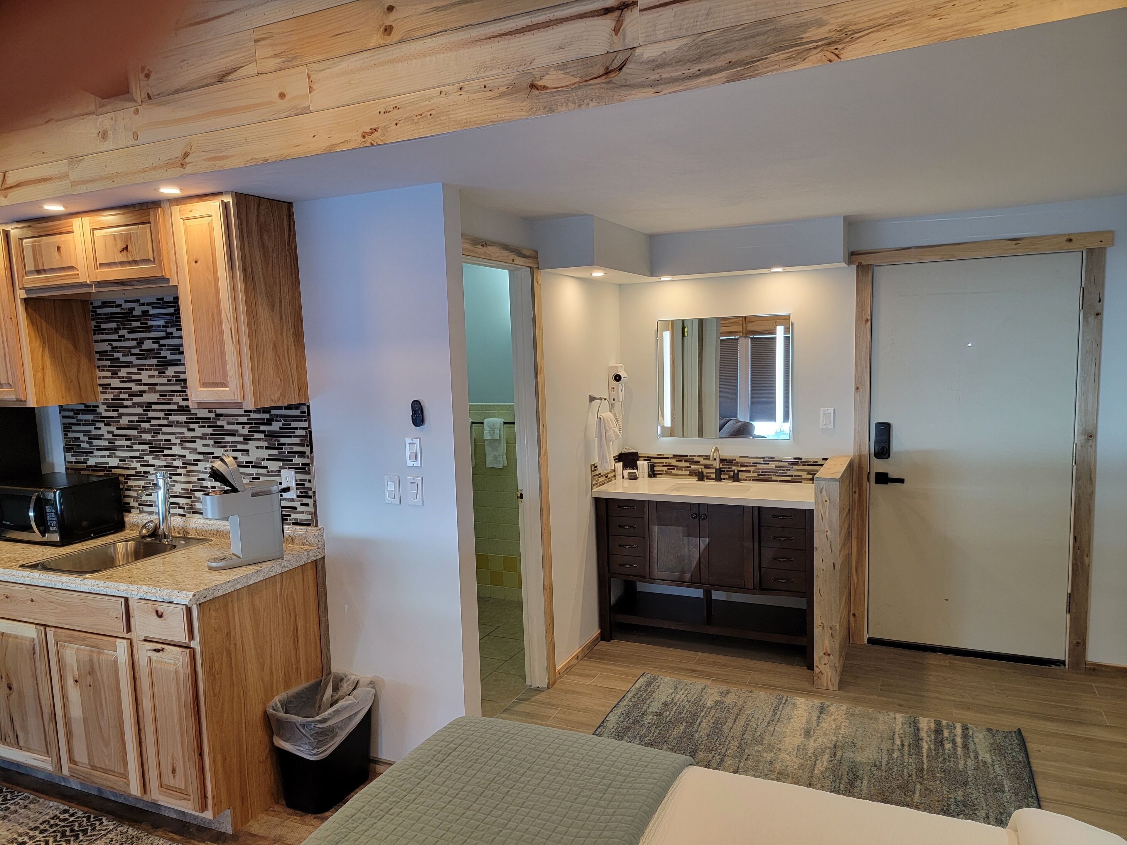 A compact kitchen with wooden cabinets, a microwave, and a sink.