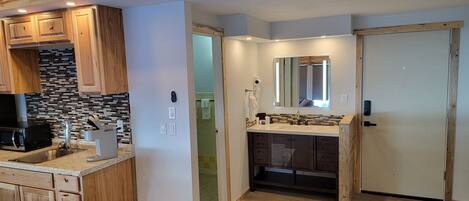 A compact kitchen with wooden cabinets, a microwave, and a sink.