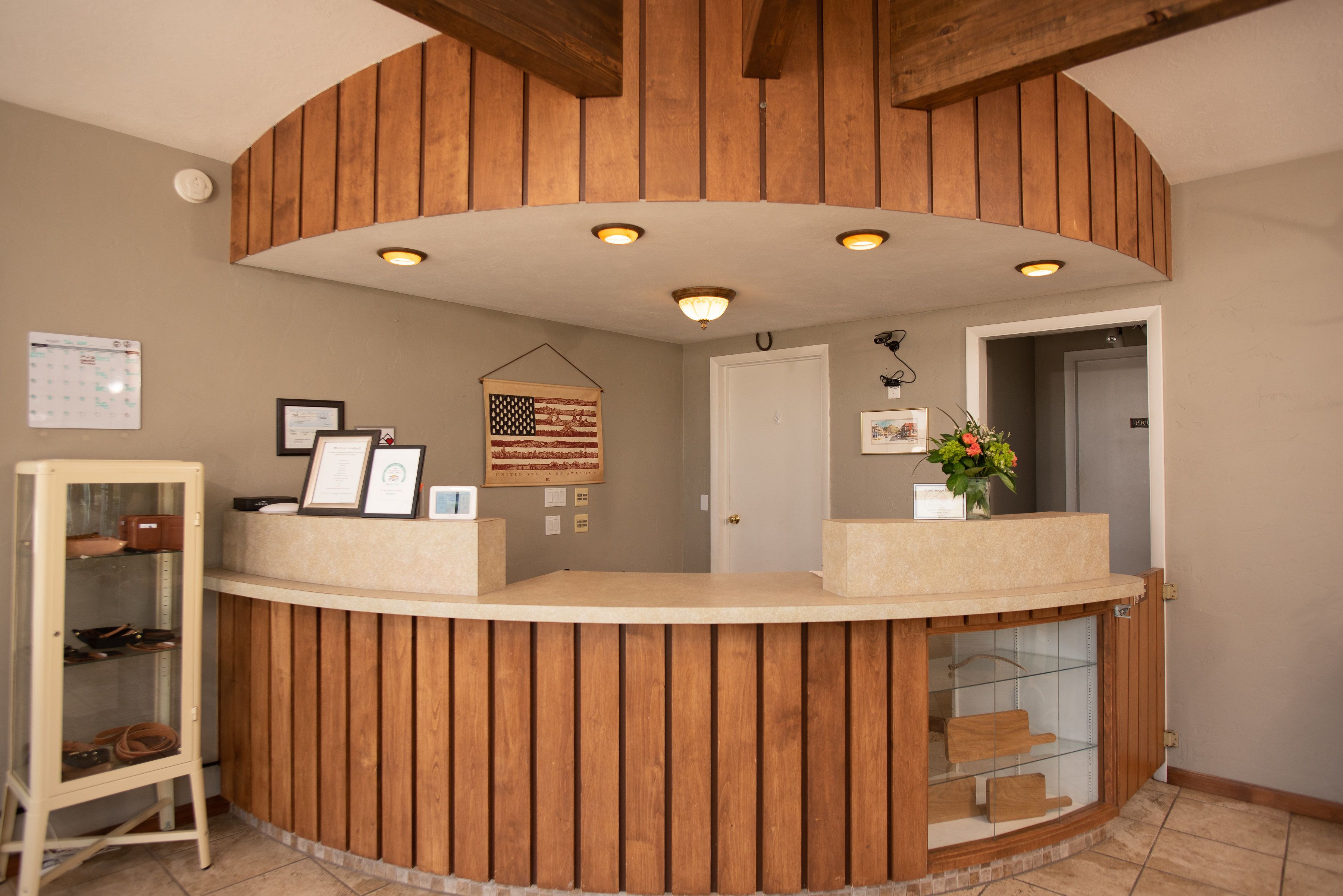 A reception desk with a wooden finish, a glass display case, and a framed American flag.