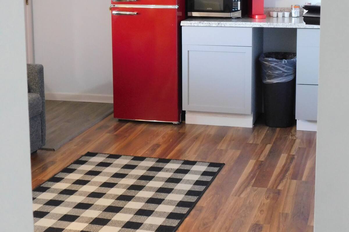 Eine kleine Küche mit einem roten Galanz-Kühlschrank, einer Mikrowelle, einer Kaffeemaschine und einem Mülleimer.