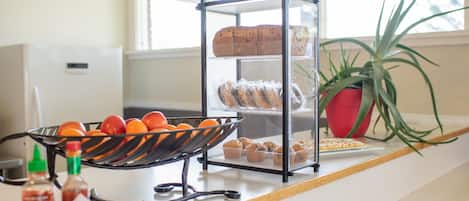 Una encimera de cocina con una exhibición de pan, un frutero y condimentos.