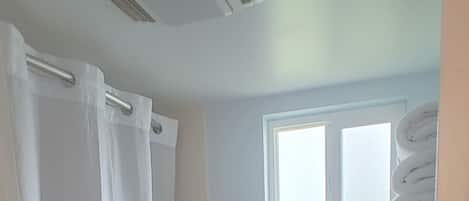 A bathroom with a bathtub, toilet, and a window above the toilet.