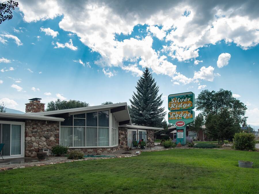 Een lodge met een stenen gevel, grote ramen en een bord dat het een Silver Ridge Lodge identificeert.