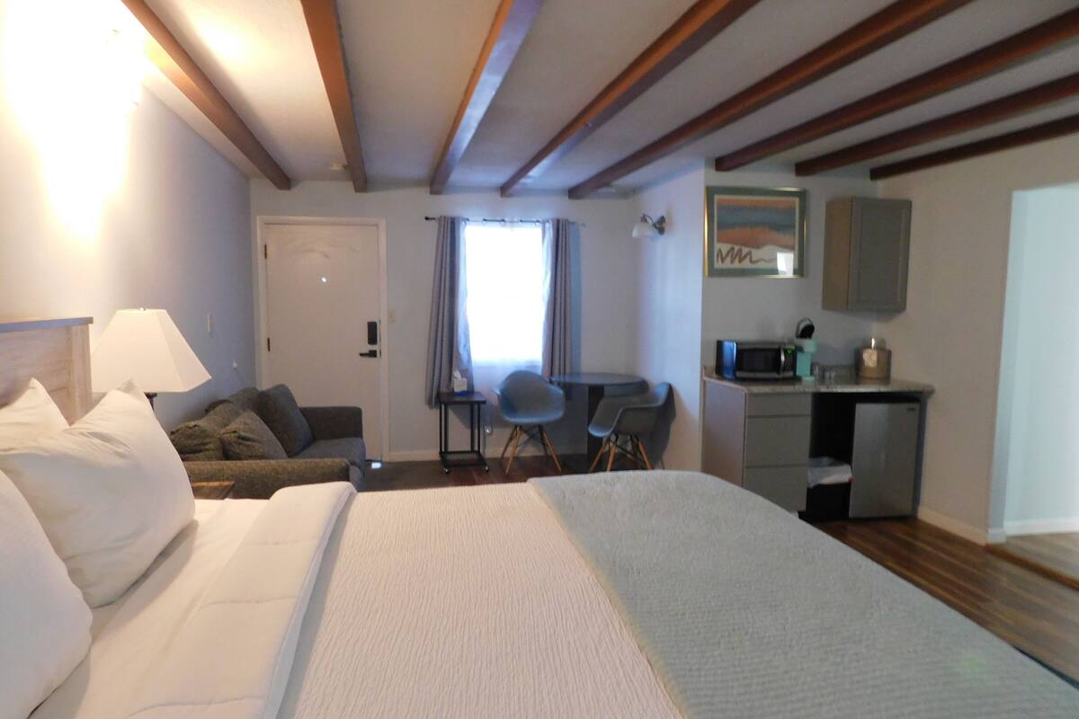 Ein Hotelzimmer mit einem großen Bett, einem Schreibtisch, einem Stuhl, einer Mikrowelle und einem kleinen Schrank.