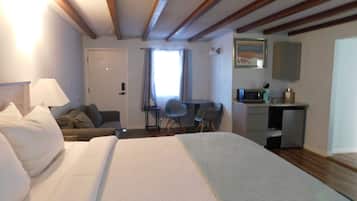 A hotel room with a large bed, a desk, a chair, a microwave, and a small cabinet.