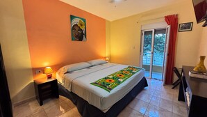 A bedroom with a bed, a nightstand, a ceiling fan, a window with curtains, and a door leading to an outdoor area. - Viva Maria Apartments (Playa del Carmen)