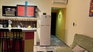 A compact living space with a kitchenette, a dining area with stools, a sofa, and a coffee table. - Viva Maria Apartments (Playa del Carmen)