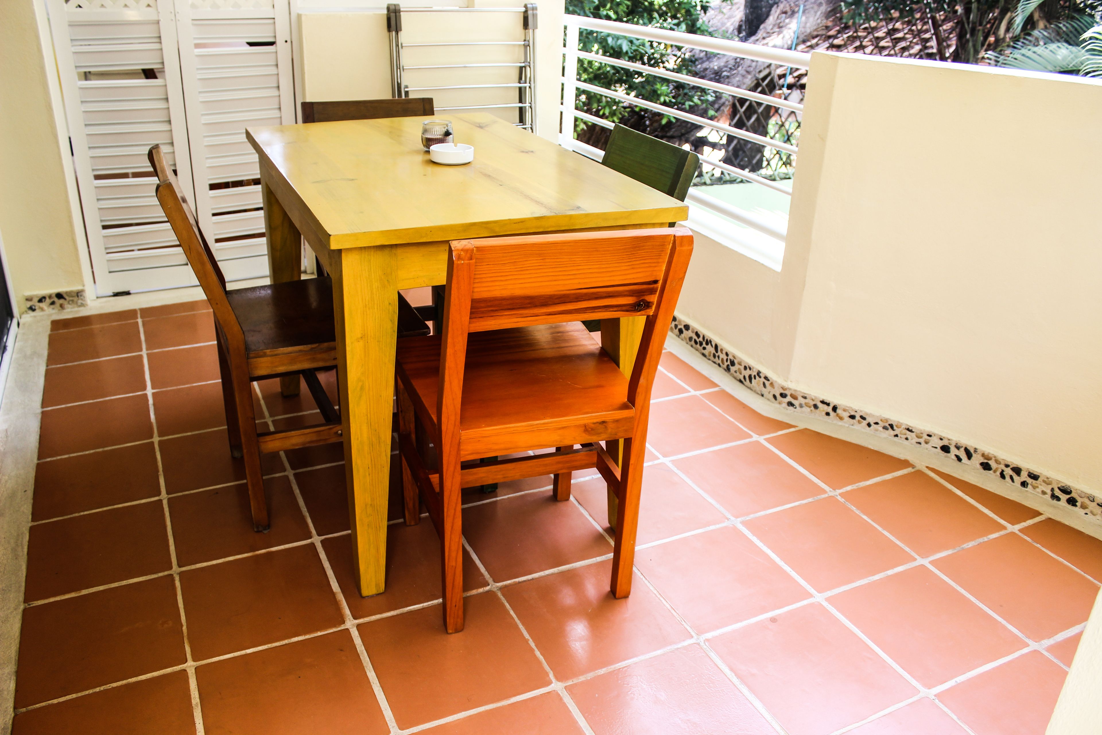 Un comedor con una mesa y sillas de madera, una ventana con vistas a zonas verdes y un suelo de baldosas.