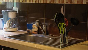 A kitchen with a sink, coffee maker, and utensils. - Viva Maria Apartments (Playa del Carmen)