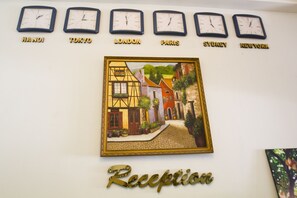 A wall with clocks labeled with city names and a framed painting of a European village.
