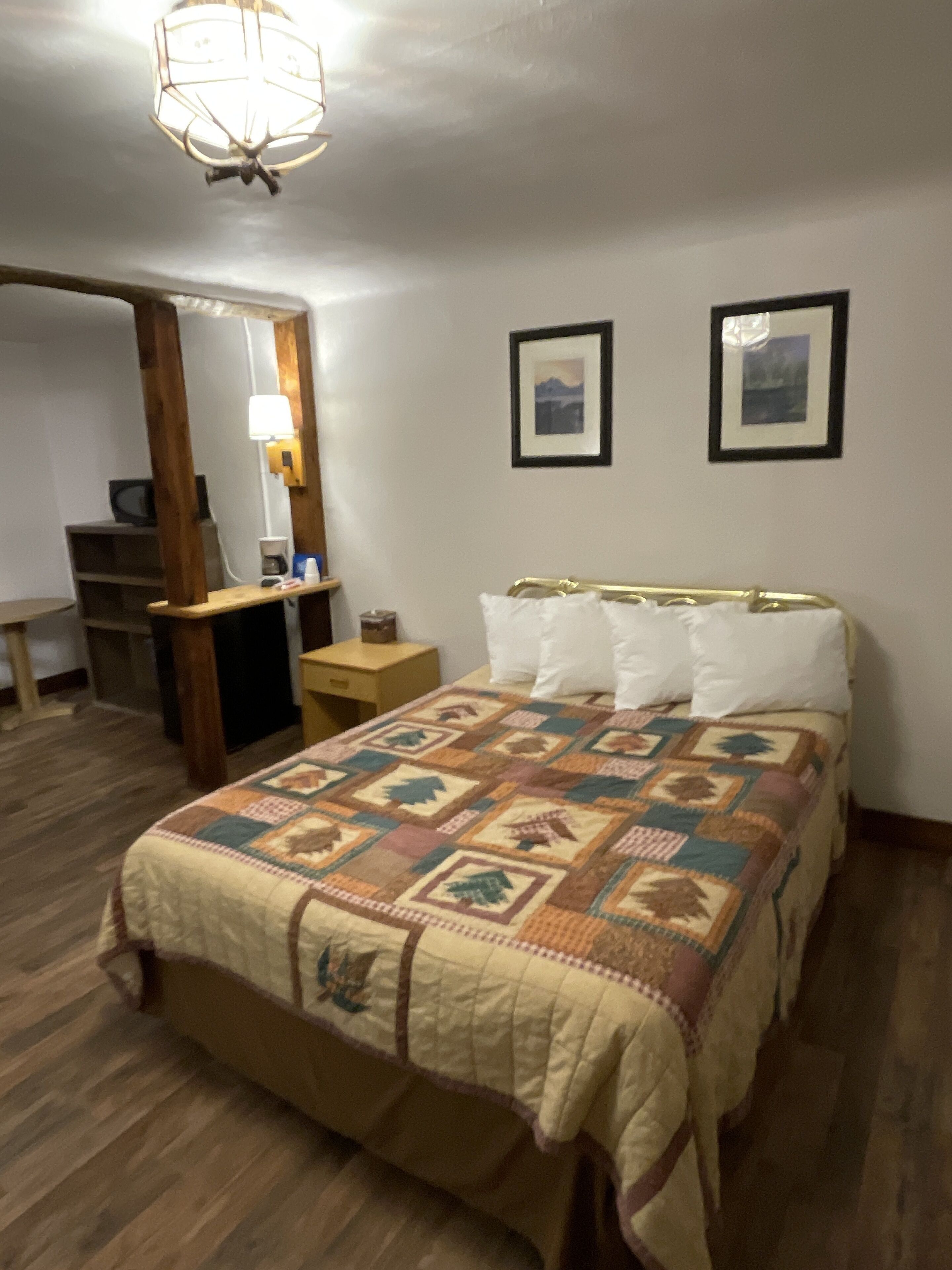 Une chambre à coucher comprenant un lit, une table de chevet, une lampe, un miroir et deux tableaux encadrés accrochés au mur.