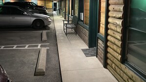Ein Motel mit überdachtem Parkplatz, einer Bank und einer Reihe von Blockhütten.