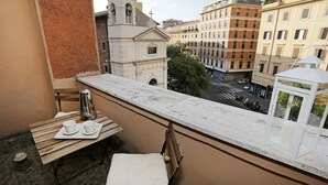En balkon med et bord, stole og udsigt til bygninger og en kirke.
