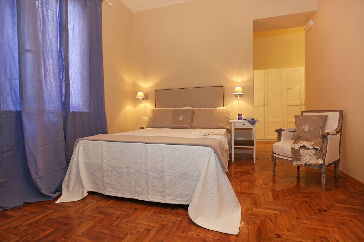 A bedroom with a bed, nightstand, chair, and a door leading to a closet.