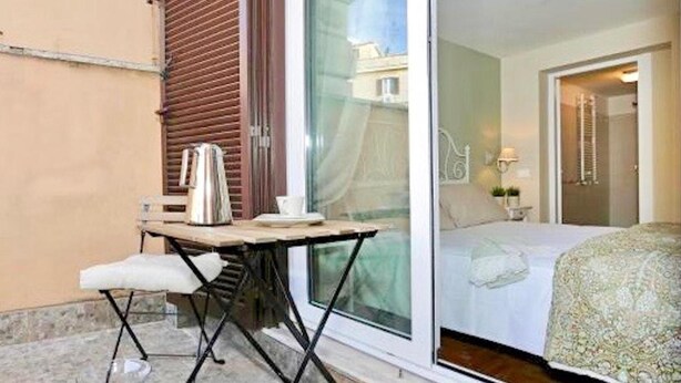En lille balkon med et bord, en stol og en elkedel.